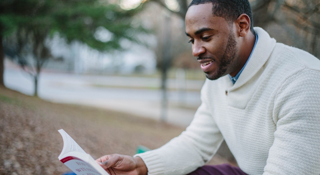 An ebony stud reading a book.